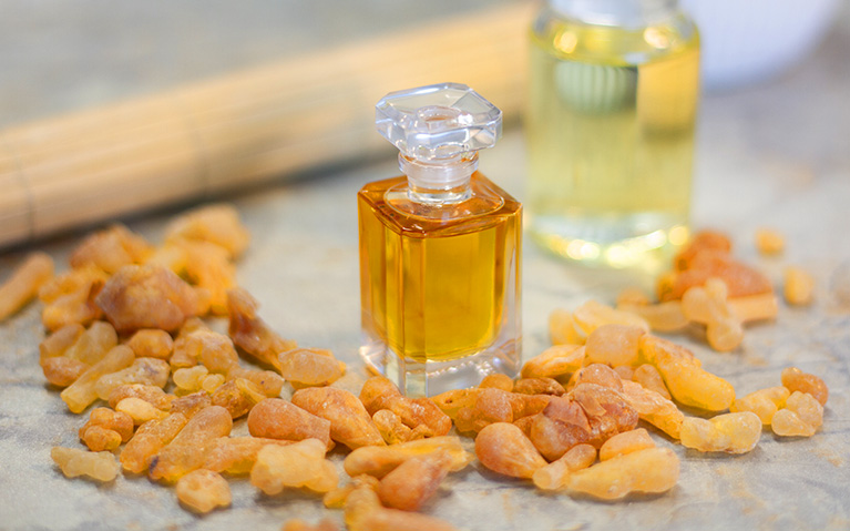 Bottle of Olibanum Essential Oil with Natural Frankincense Resin Surrounding It
